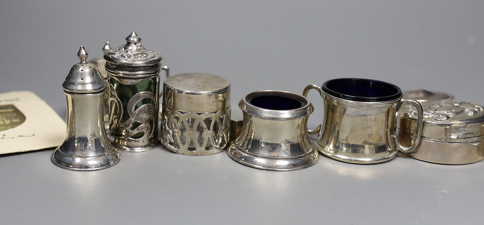 A small group of collectable small silver and white metal items including two pairs of 19th century sugar tongs(one a.f.), later condiments, match sleeve, dish pill box, etc.